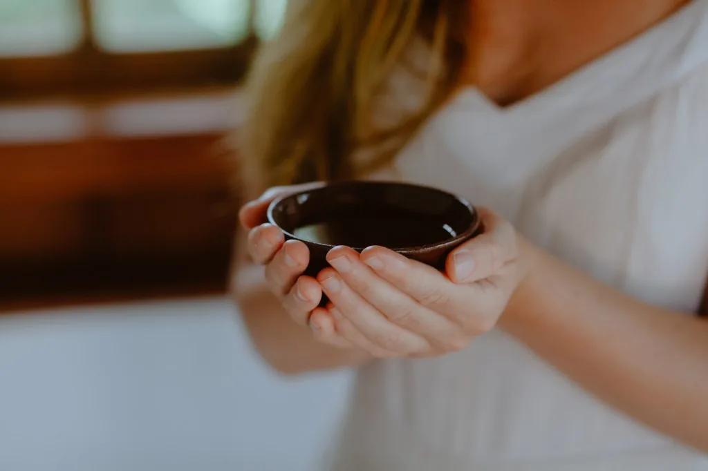 Mãos de Naiara Lofgren segurando recipiente terapêutico